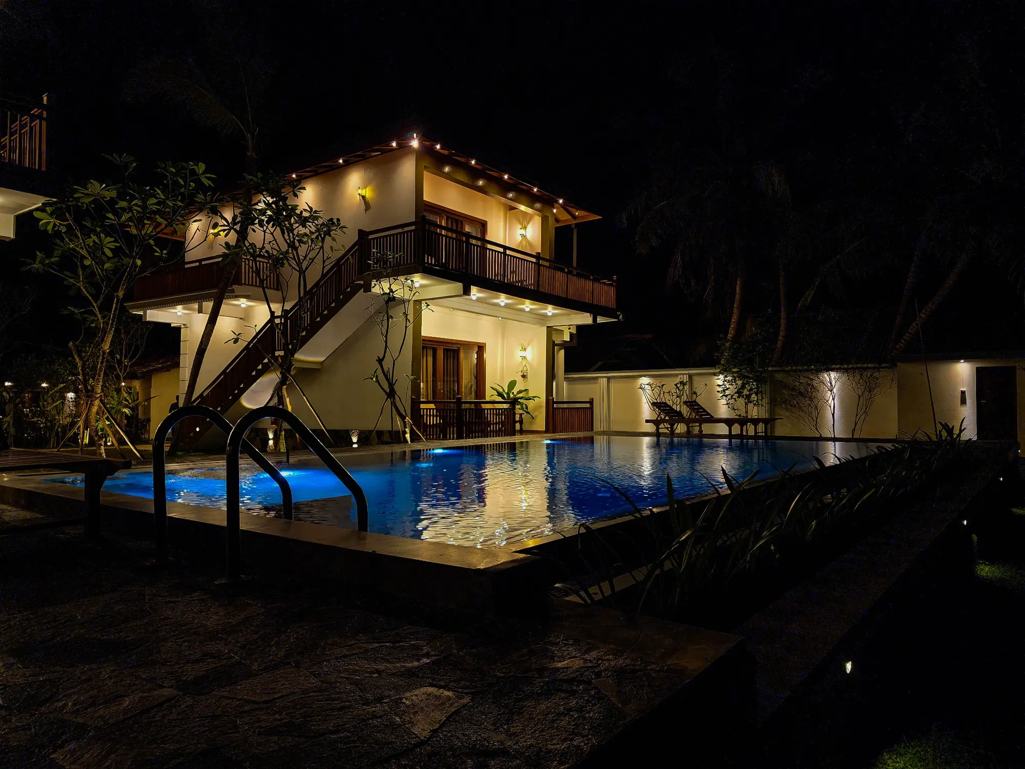 Illuminated villa and swimming pool photographed at night