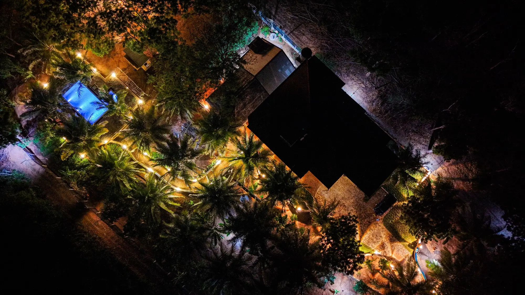 Night aerial view of a tropical resort with illuminated pool and gardens