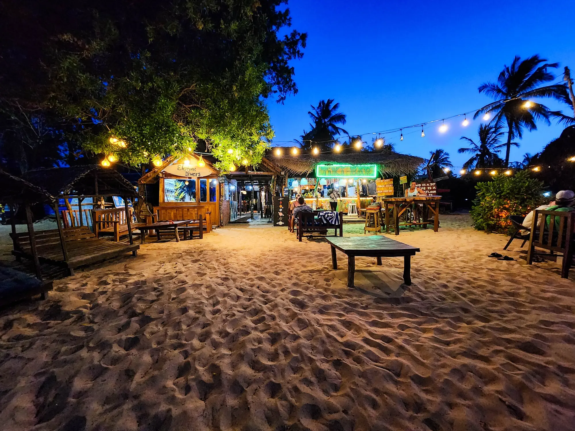 Beachfront restaurant glowing beneath string lights at blue hour